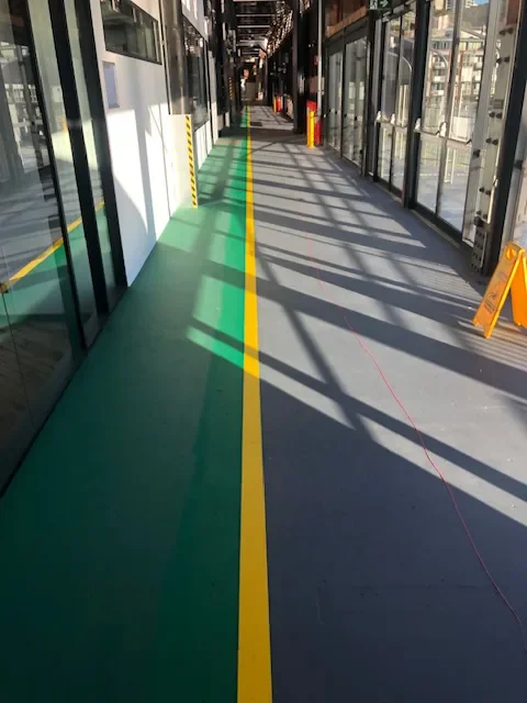 Green and grey floor zones divided by a yellow boundary line in a commercial building